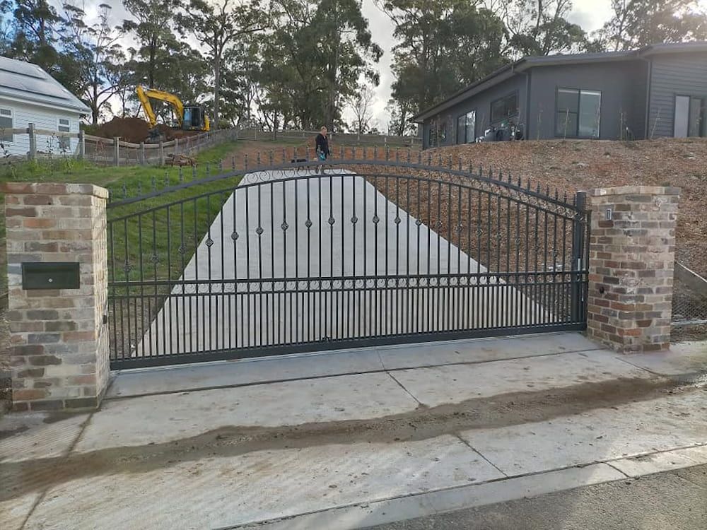 A Man is Standing in Front of a Gate in Front of a House — Southern Gate Automation in Mittagong, NSW