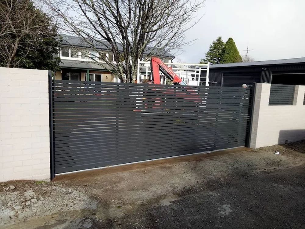 A Fence with a Sliding Gate in Front of a Building — Southern Gate Automation in Moss Vale, NSW