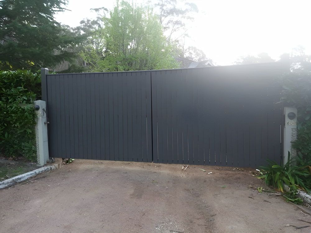 A Black Gate is Sitting on the Side of a Dirt Road — Southern Gate Automation in Bowral, NSW