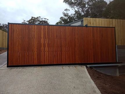 A Large Wooden Fence is Sitting on a Gravel Driveway — Southern Gate Automation in Mittagong, NSW