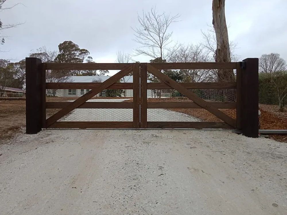 A Wooden Gate is Sitting on the Side of a Gravel Road — Southern Gate Automation in Mittagong, NSW