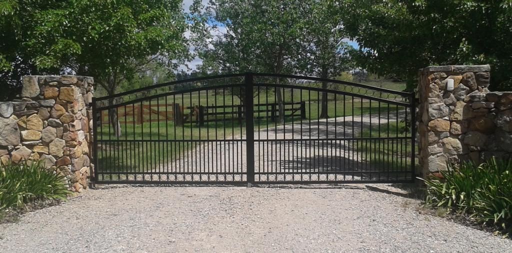 A Wrought Iron Gate With a Stone Wall Behind It — Southern Gate Automation in Mittagong, NSW