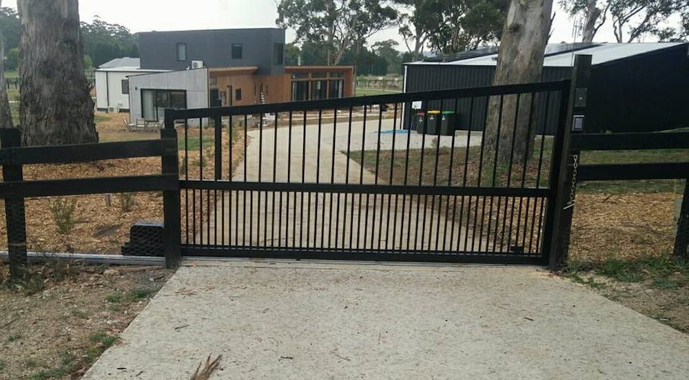 A Black Gate with a Wooden Fence in Front of a House — Southern Gate Automation in Goulburn, NSW