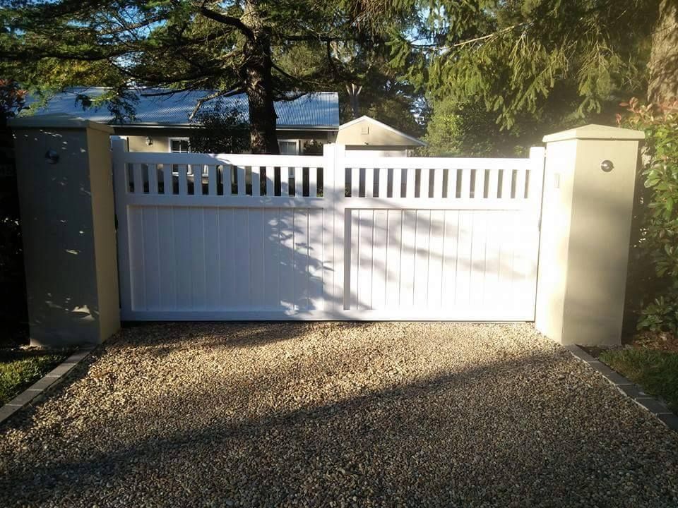 A White Gate is Sitting in the Middle of a Gravel Driveway — Southern Gate Automation in Mittagong, NSW