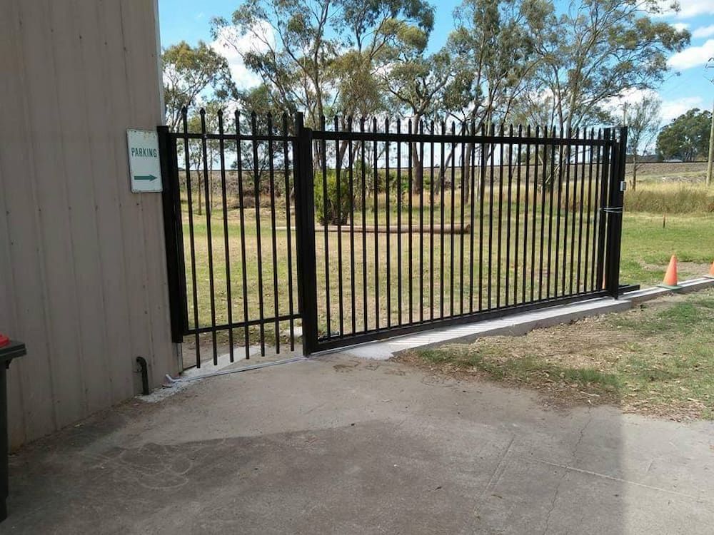 A Black Metal Gate is Sitting in Front of a Building — Southern Gate Automation in Bowral, NSW