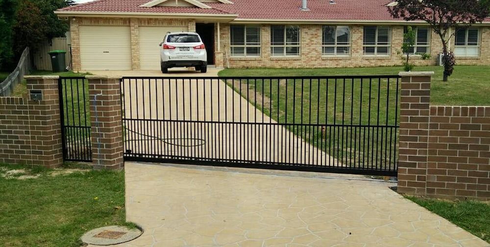 A Car is Parked in Front of a House with a Sliding Gate — Southern Gate Automation in Goulburn, NSW