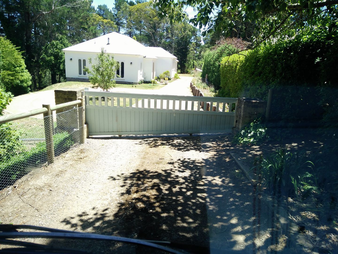 A white house has a white electric fence in the driveway — Southern Gate Automation in Picton, NSW