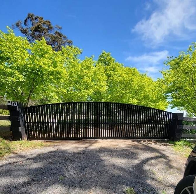 A Man is Standing in Front of a Gate on a Gravel Road — Southern Gate Automation in Mittagong, NSW