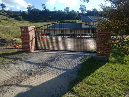 A Brick Wall with a Metal Gate in Front of a House — Southern Gate Automation in Mittagong, NSW