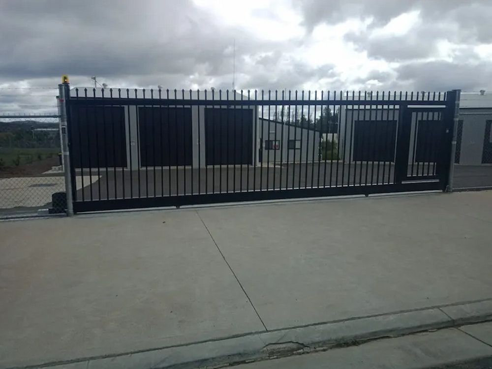 A Black Sliding Gate is Closed in Front of a Building — Southern Gate Automation in Bowral, NSW