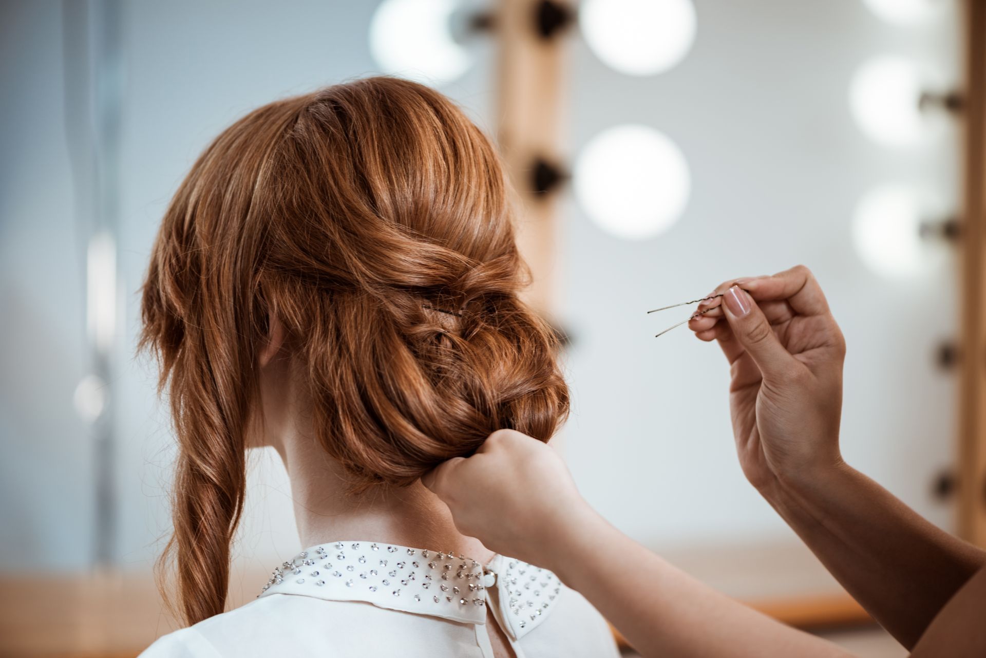A woman is getting her hair done by a hairdresser in front of a mirror.