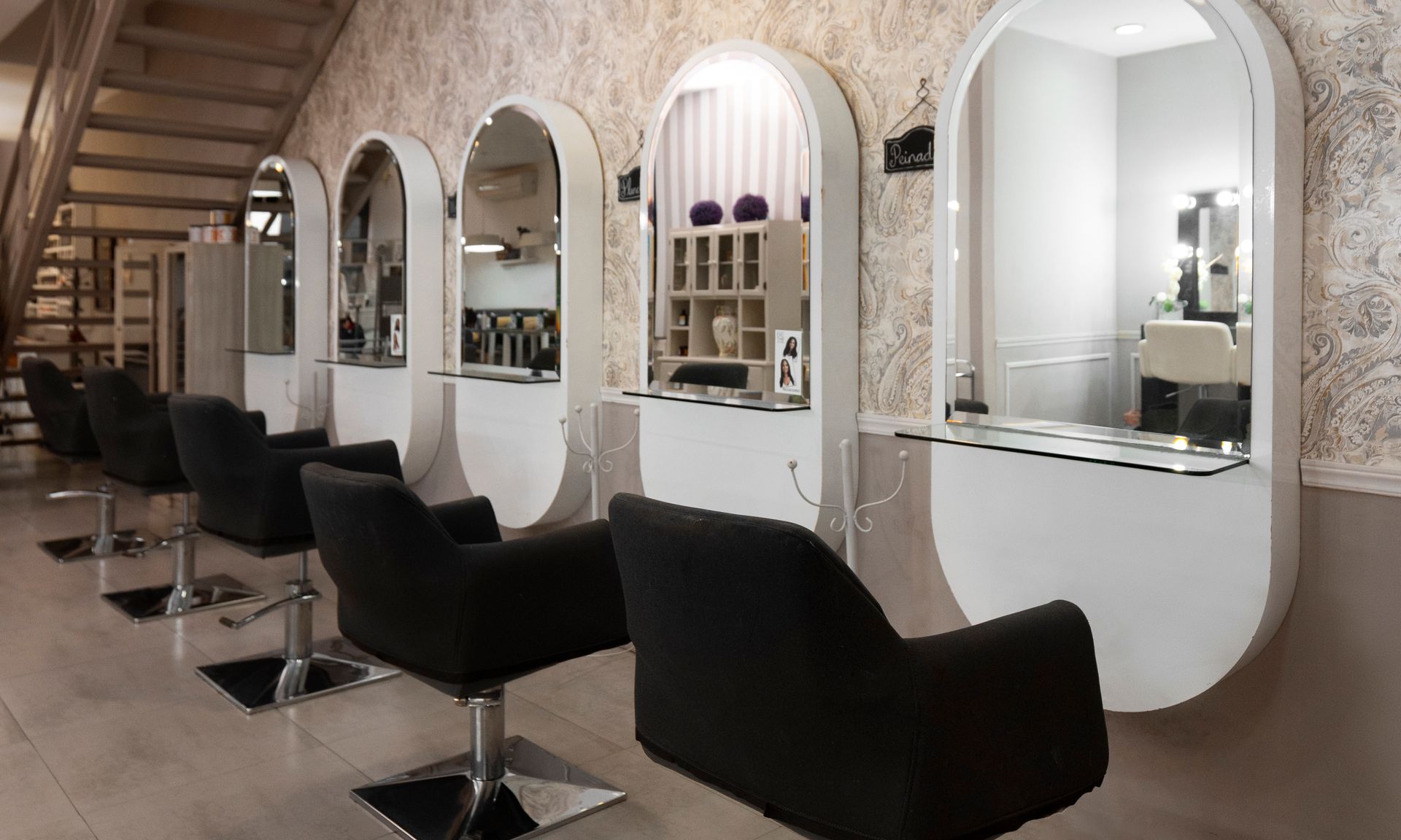 A row of chairs in a hair salon with mirrors on the wall.