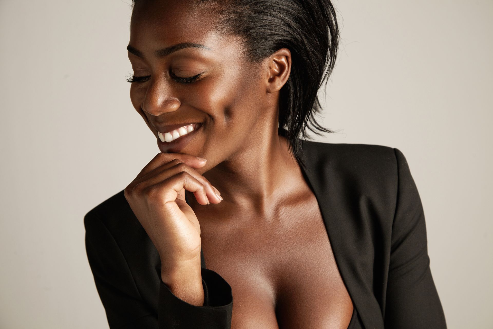 A woman in a black jacket with a very plunging neckline is smiling.