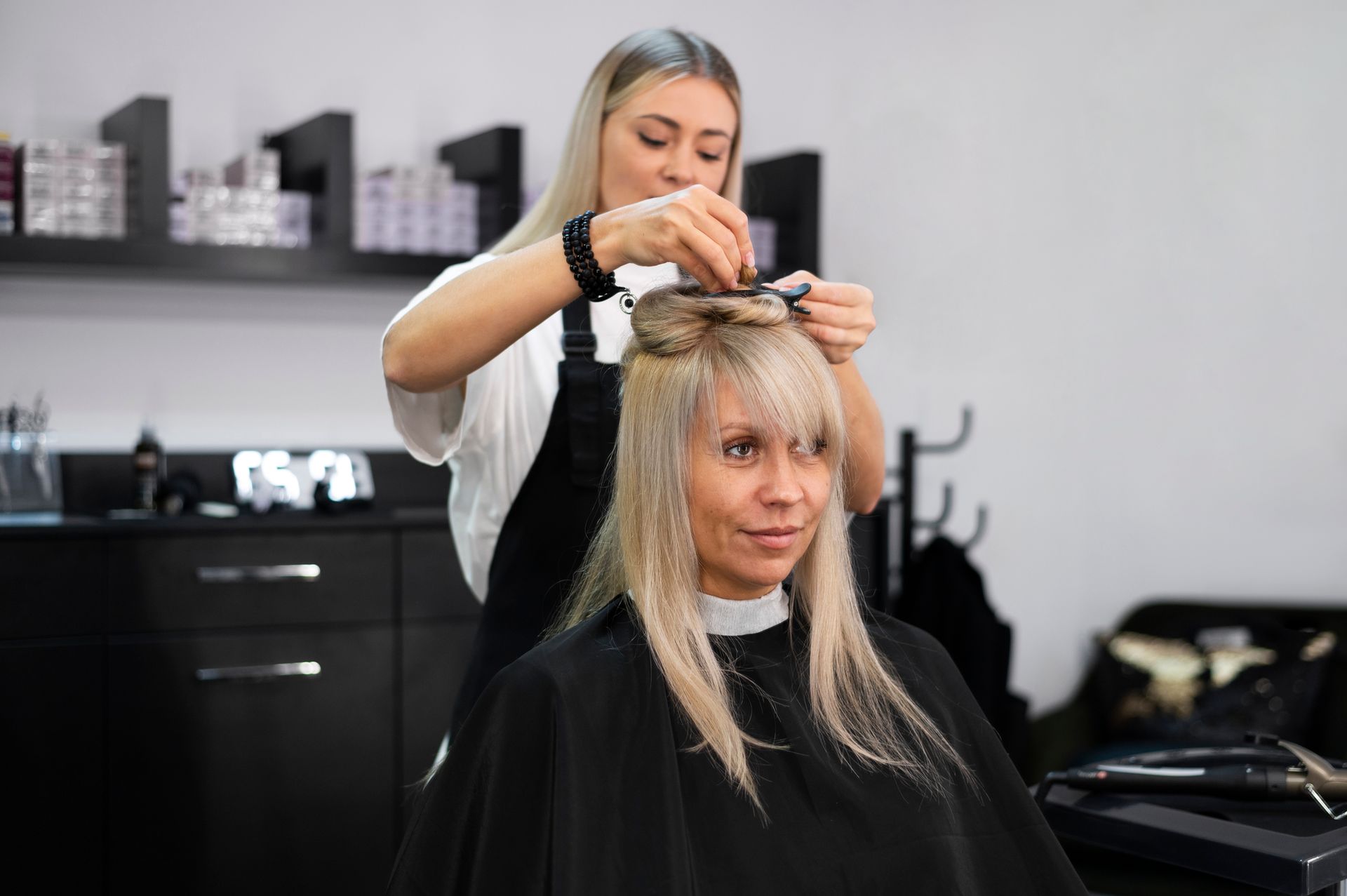 A woman is getting her hair cut by a hairdresser in a salon.