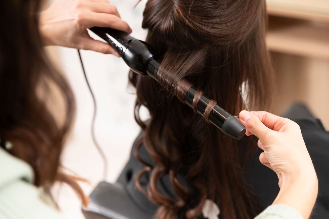A woman is getting her hair curled by a hairdresser.