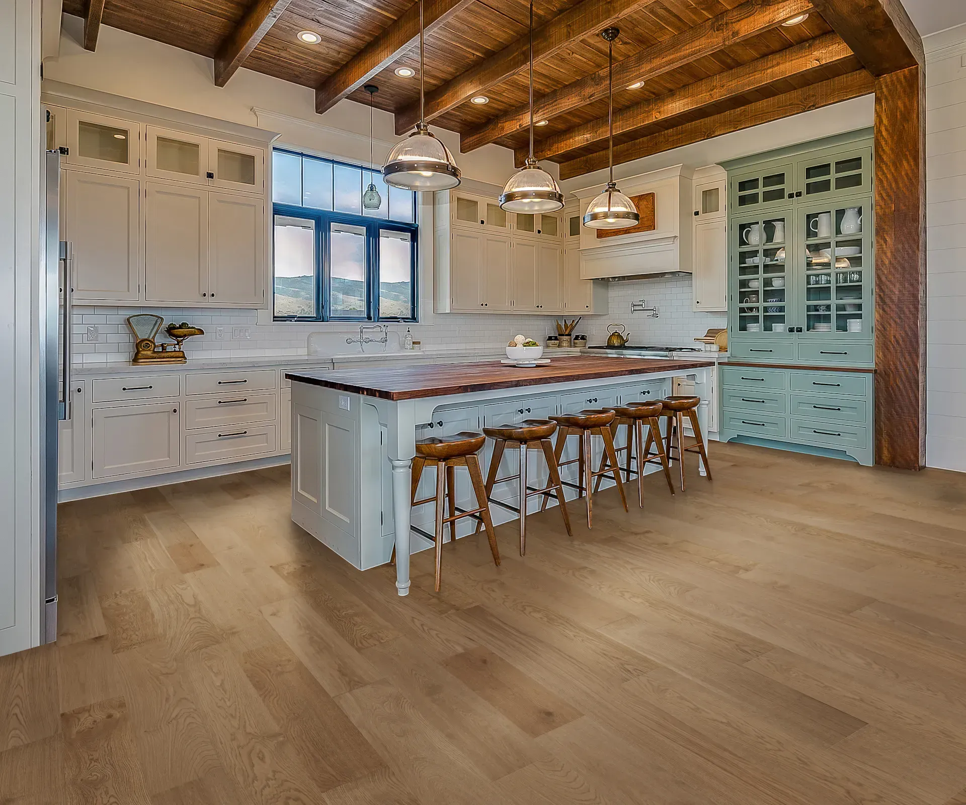 Spacious kitchen with island, wood floors, white cabinets, and a mint-green cabinet, wooden ceiling with pendant lights.