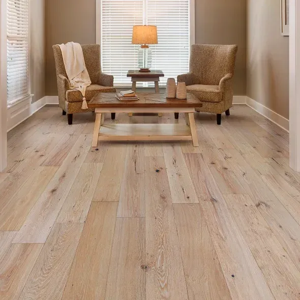 Hardwood floor in a living room with two armchairs, a coffee table, and a window with blinds.
