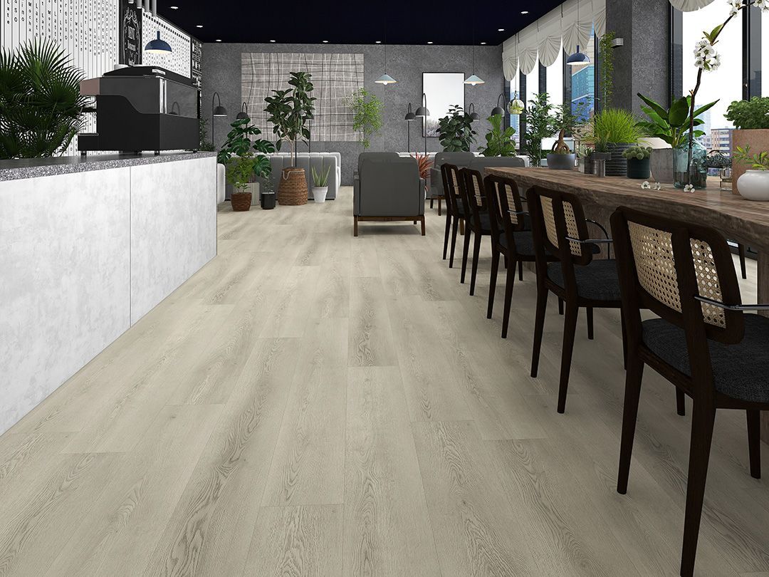 A light-colored wooden floor in a cafe with tables, chairs, and plants.