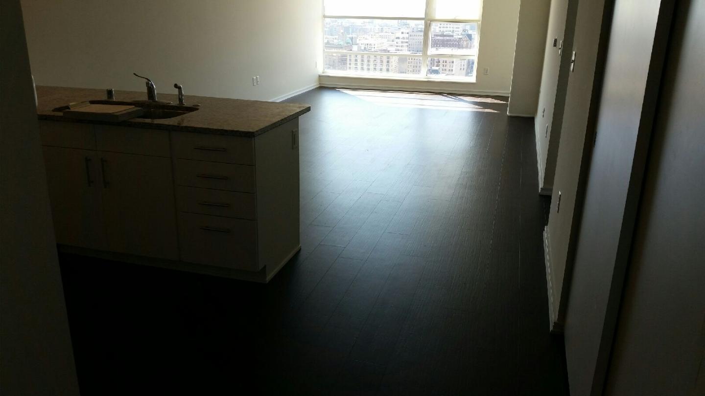 Interior view of a kitchen with dark flooring, white walls, and a window with natural light.
