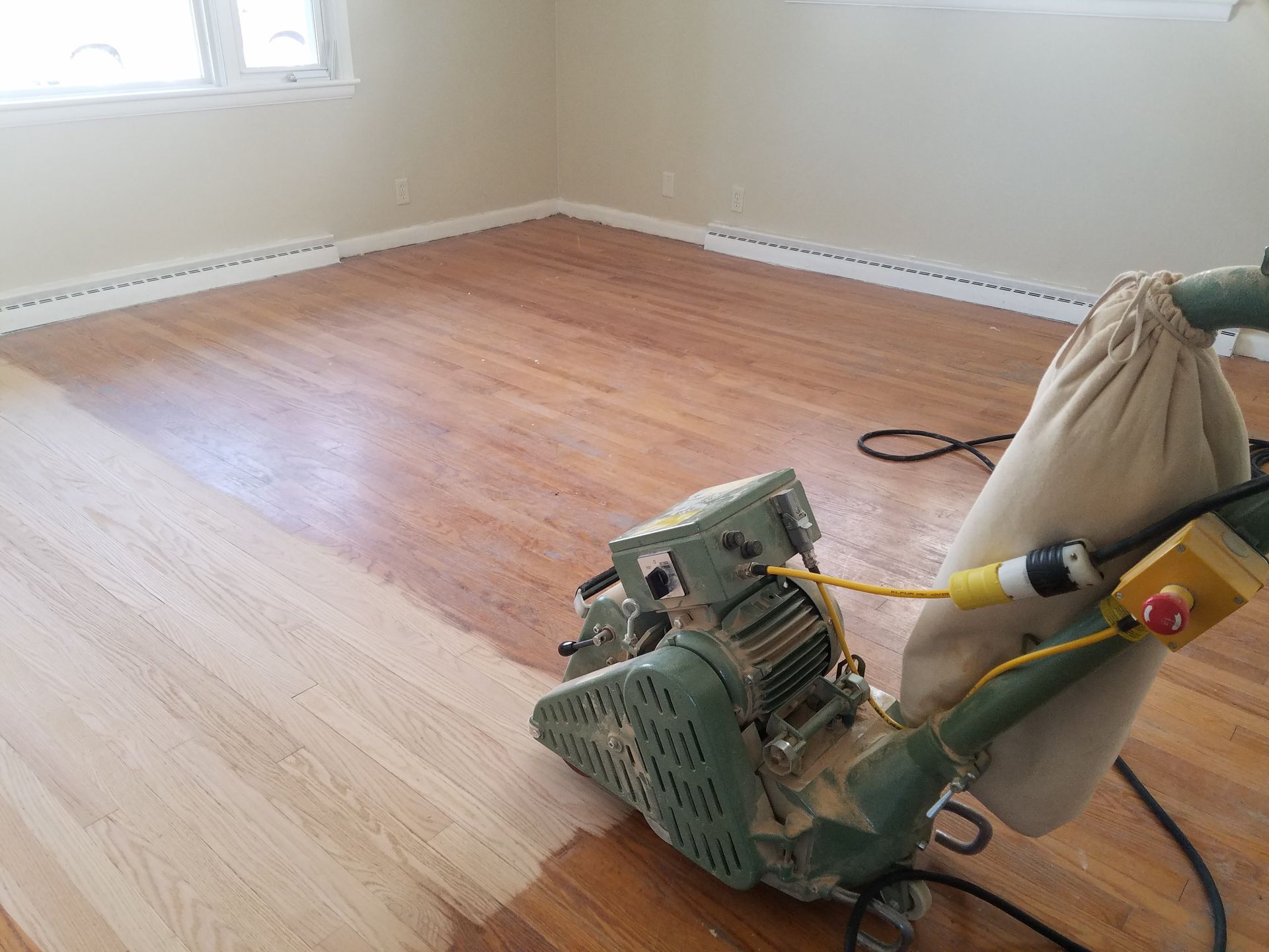 A machine is sanding a wooden floor in a room.
