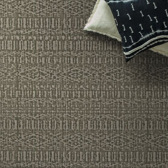 Brown patterned rug with two pillows on top, one white and one dark blue.
