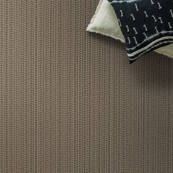 Tan carpet with a textured vertical pattern; decorative pillows rest at the top right corner.