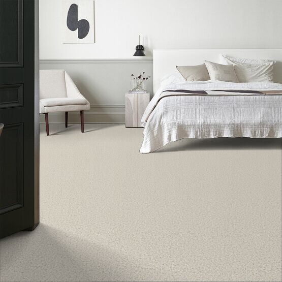 A bedroom with a bed , chair , and carpet.