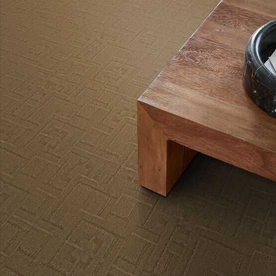 Close-up of brown textured carpet and wooden table with a bowl.