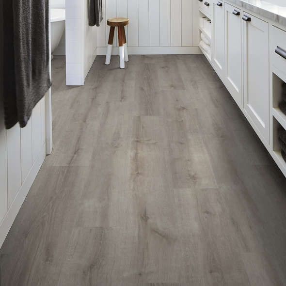 Gray wood-look flooring in a white bathroom with cabinets and a small stool.