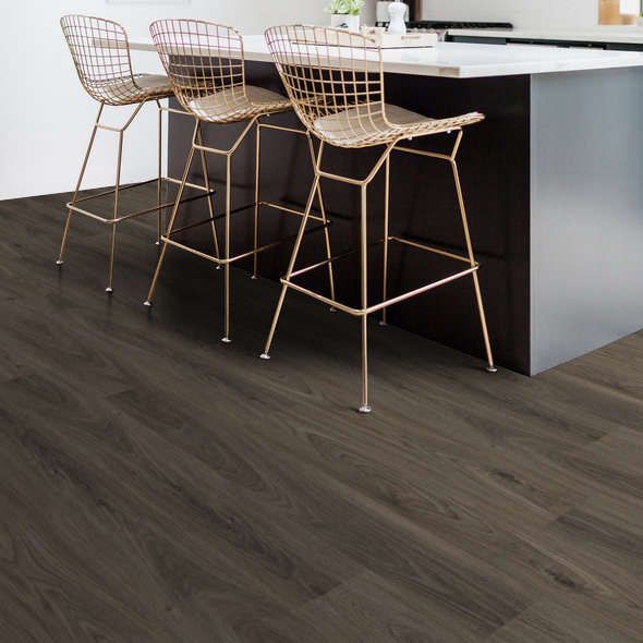 Dark wood-look flooring in a kitchen with a countertop and gold wire bar stools.