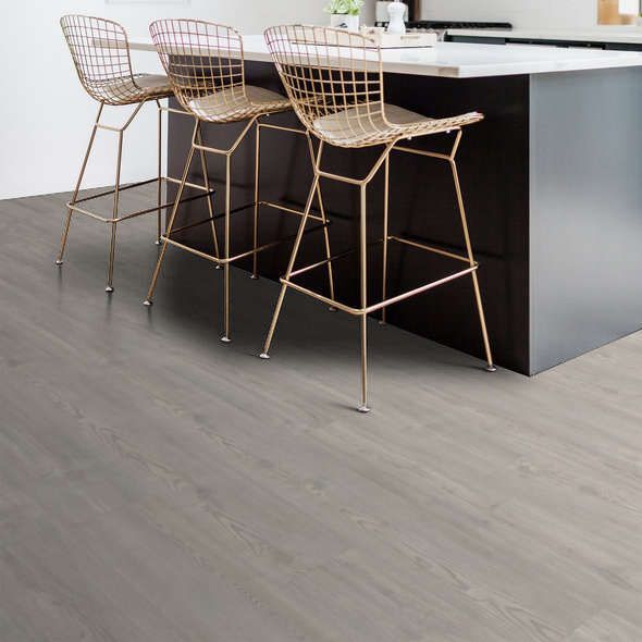 Three gold wire bar stools at a dark gray kitchen island on gray wood-look flooring.