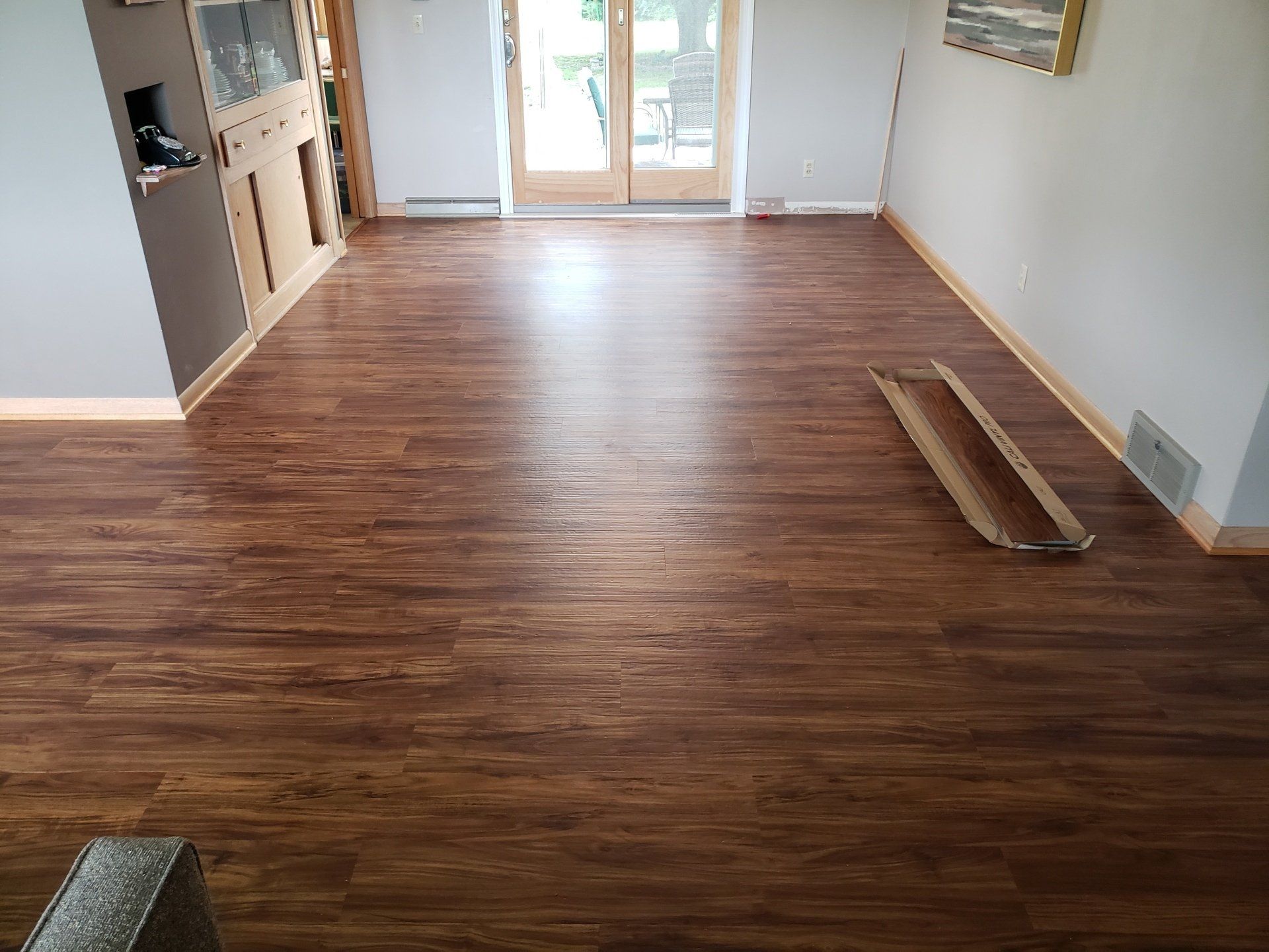 Room with brown wood-look flooring, cabinets on the left, and a doorway to a deck in the back.