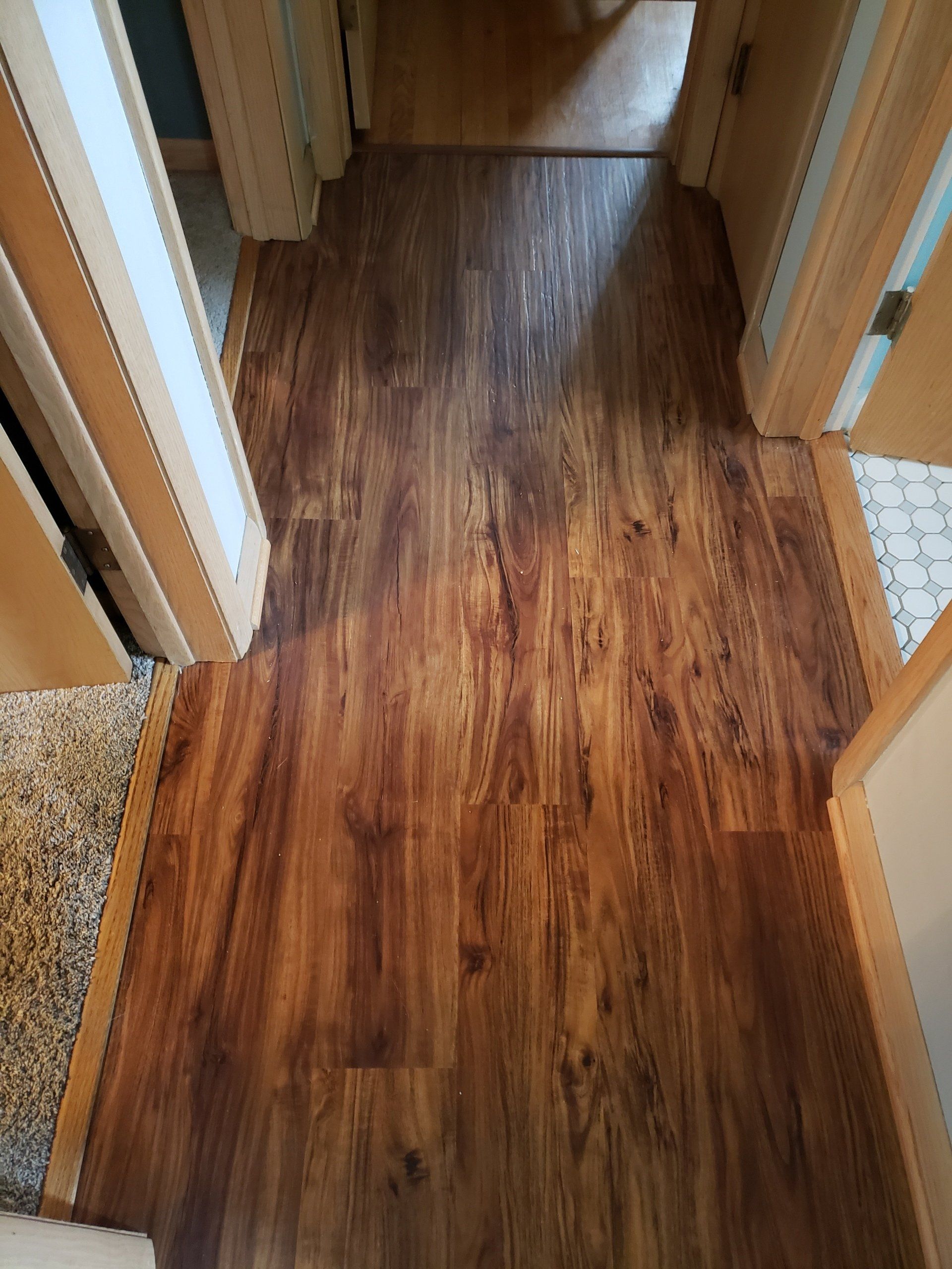 Wood-look laminate flooring in a hallway between doorways.