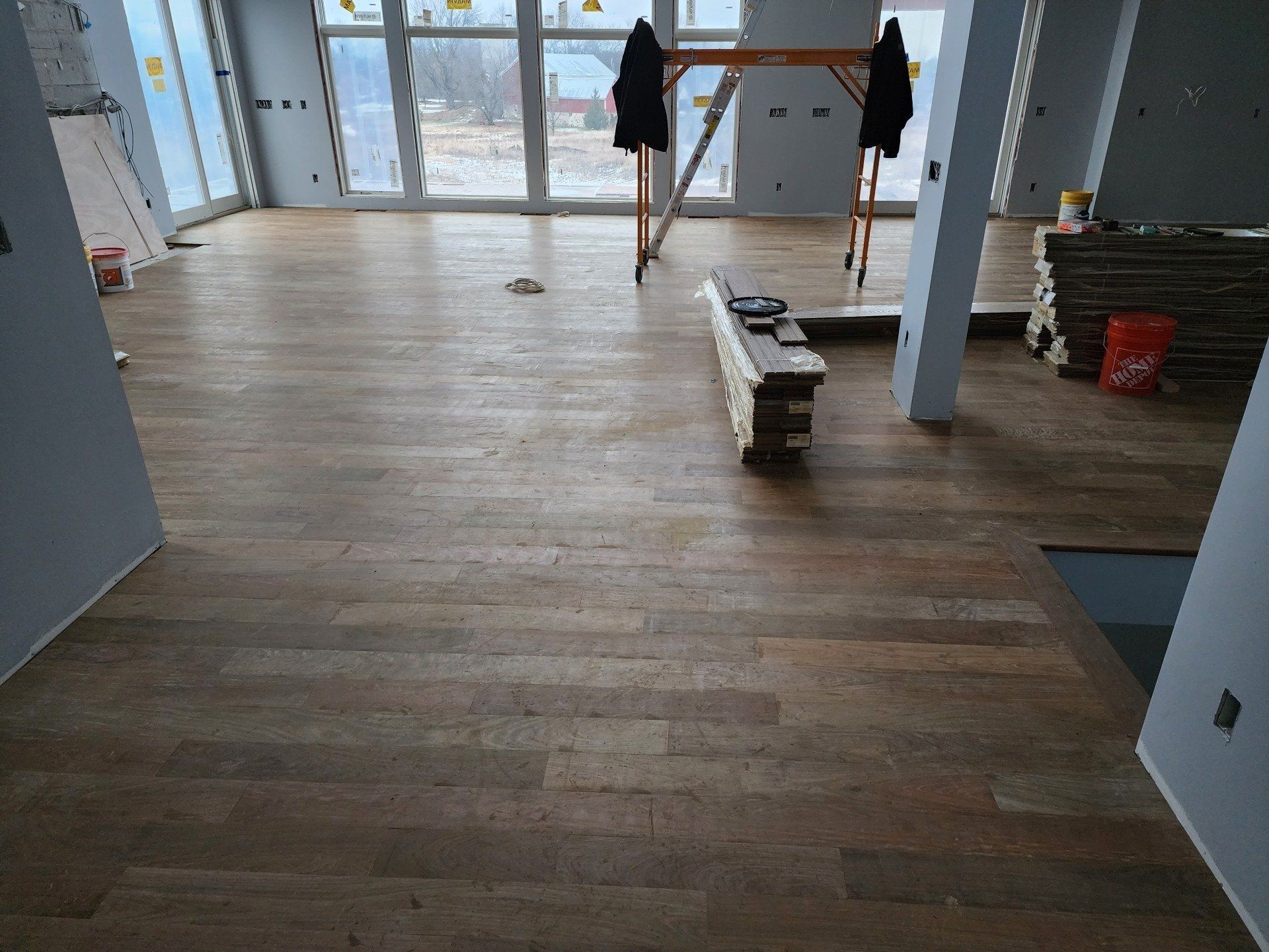 Hardwood floor installation in a modern house with large windows.