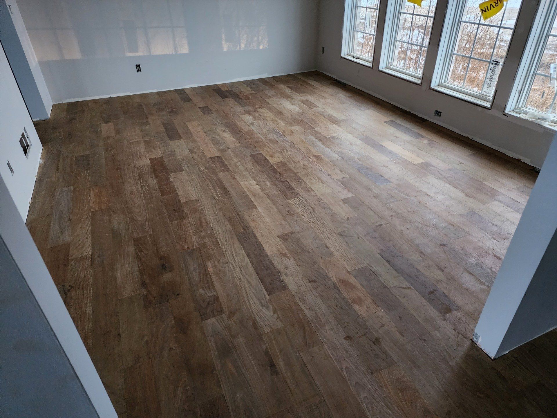 Hardwood floor in a room with windows, light walls.