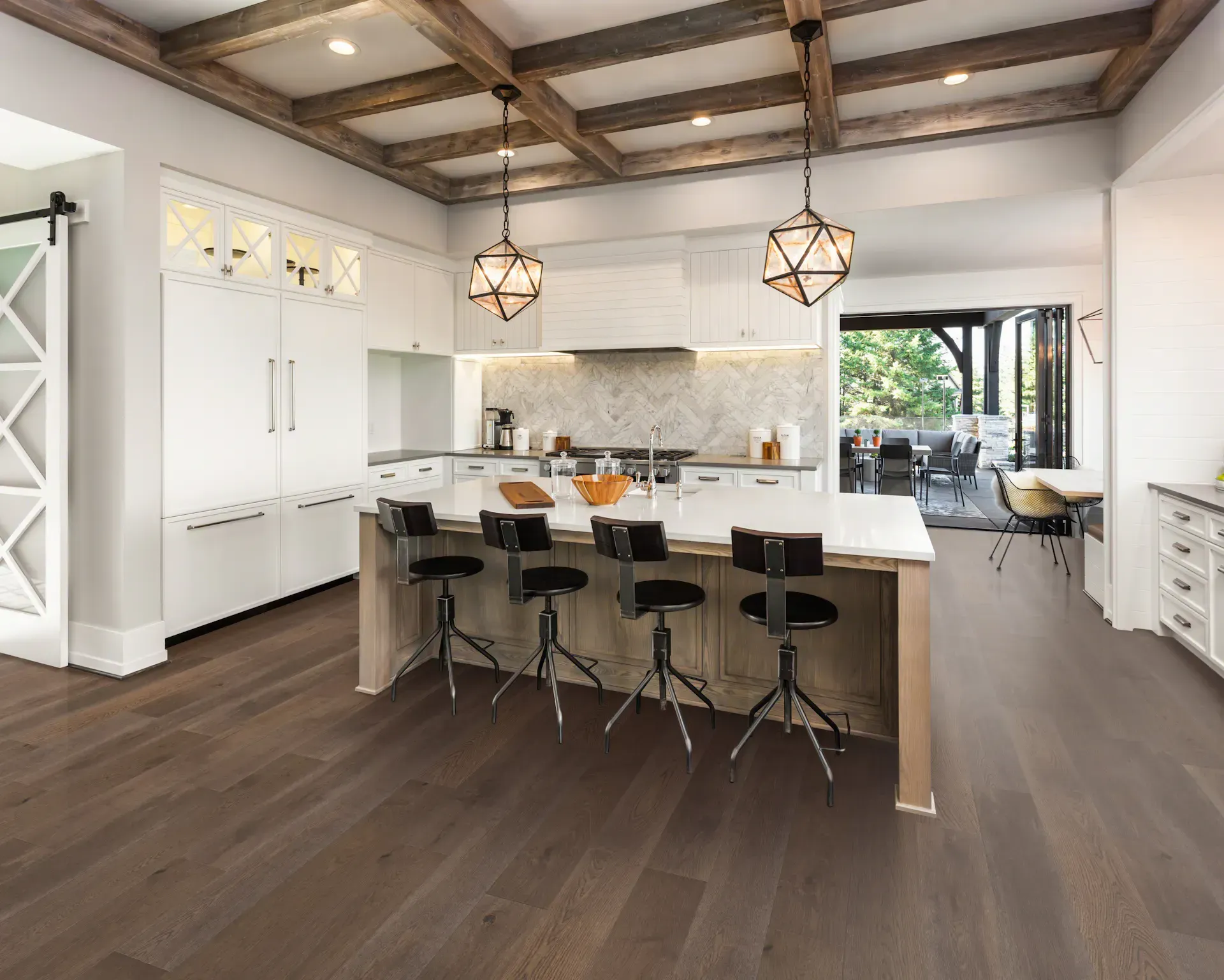 Spacious, bright kitchen with wood floors, large island with stools, and a view to a patio.