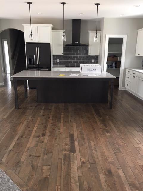 Kitchen with dark island, white cabinets, wood floors, and black appliances.