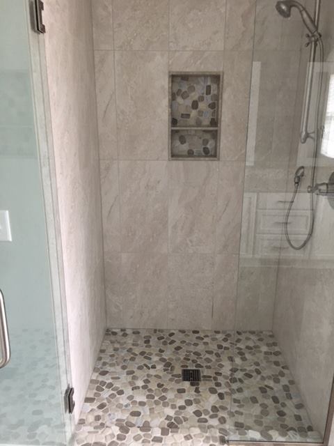 Bathroom with stone tile floor and shower with a built-in shelf.