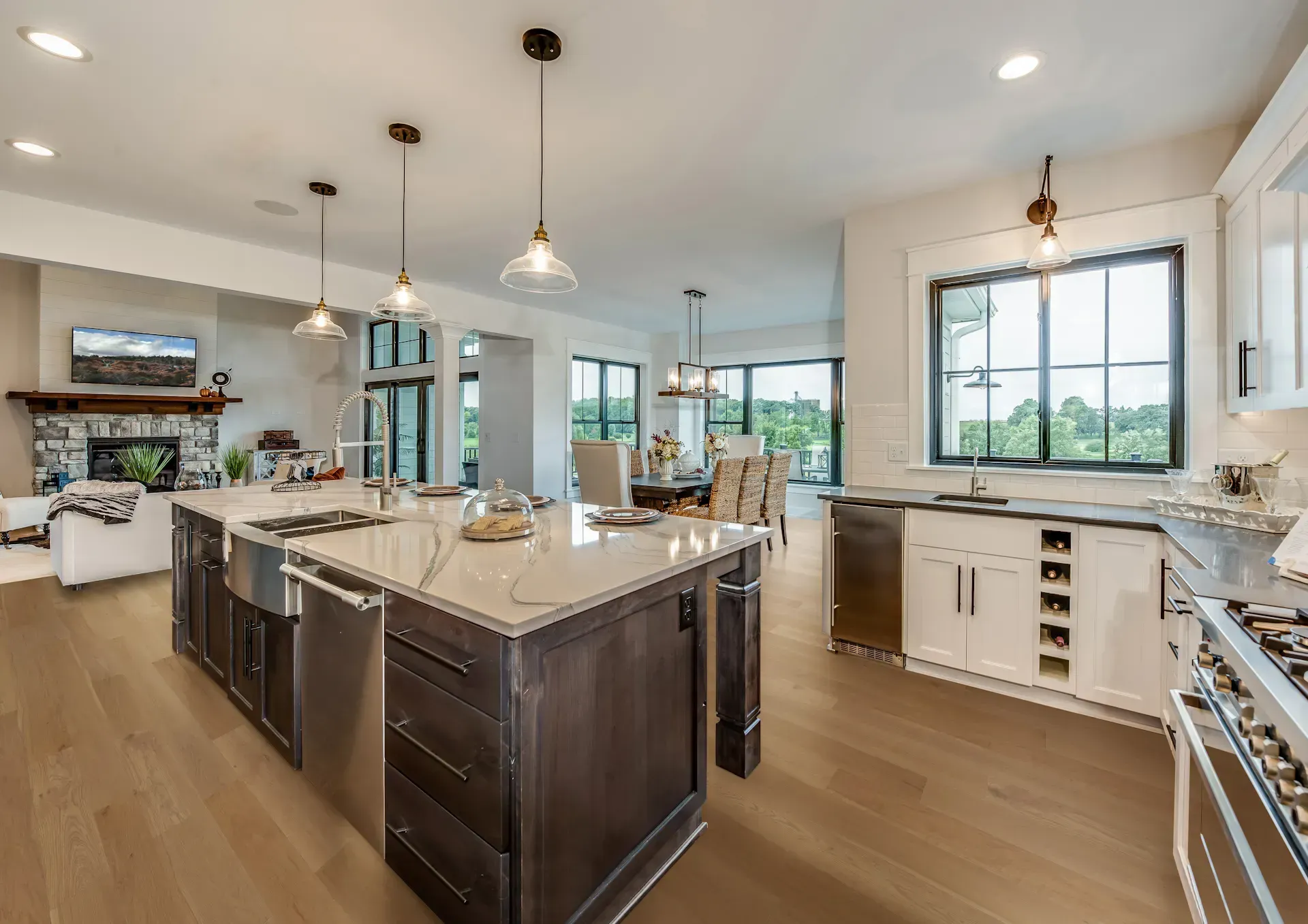 Modern kitchen with a large island, light wood floors, and stainless steel appliances.