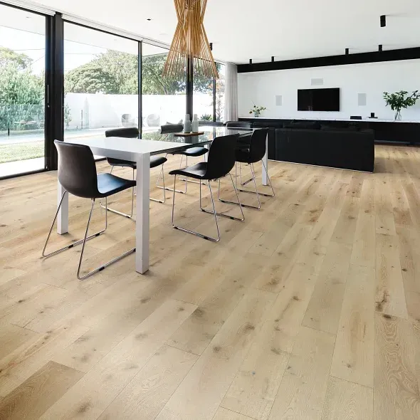 Dining room with light wood floor, white table and black chairs, large windows, and contemporary decor.