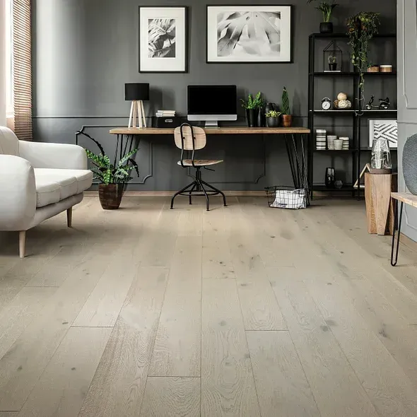 Light wood floor in a modern office with desk, computer, chair, plants, and shelves. Dark gray walls, neutral colors.
