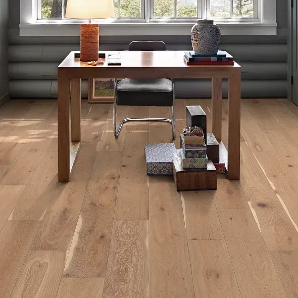 Wooden desk with chair in a sunlit room, hardwood floor, objects on the desk and floor.