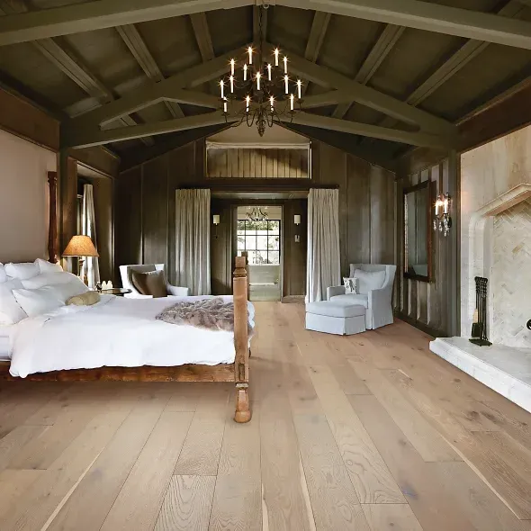 Bedroom with wooden floors, walls, and ceiling, a bed, fireplace, and chandelier.
