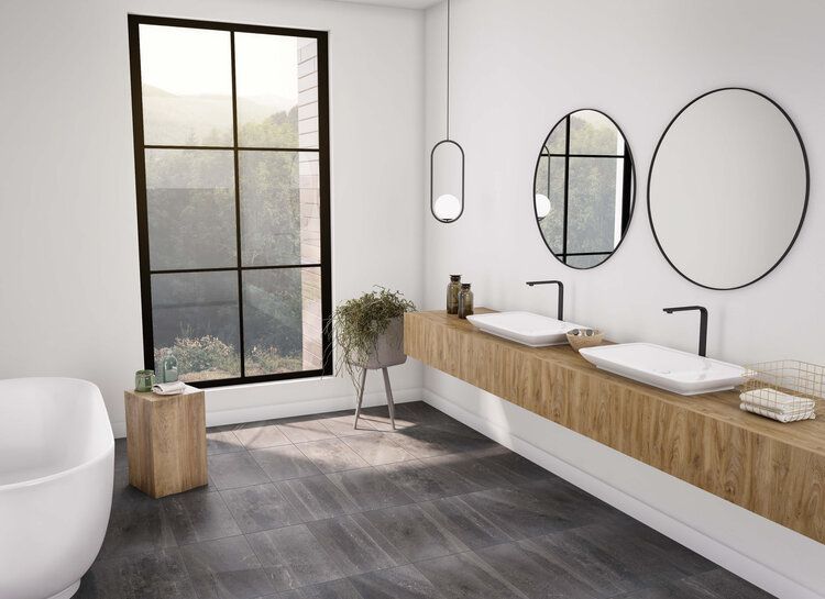 A bathroom with two sinks , a tub , two mirrors and a window.