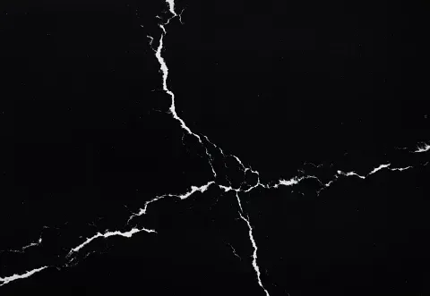 Black surface with white cracks radiating outwards.