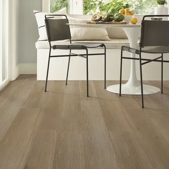 Light wood-look flooring in a bright room with black chairs, and a round table set for dining.