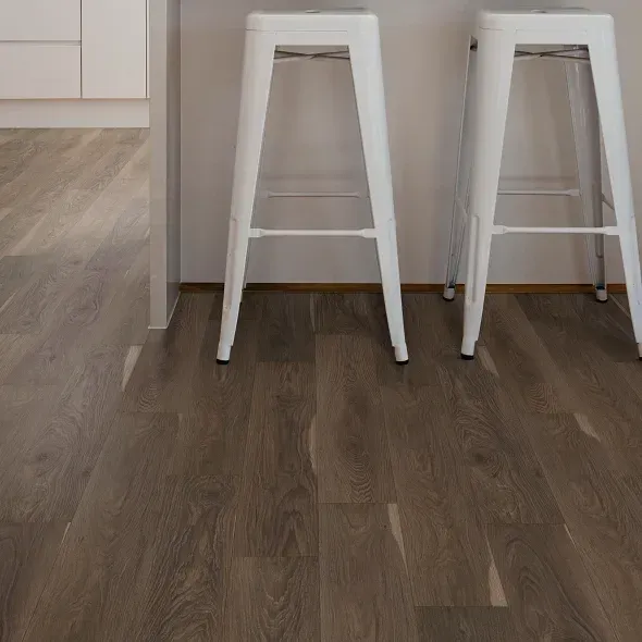 Two white bar stools on dark wood-look flooring in front of a white countertop.