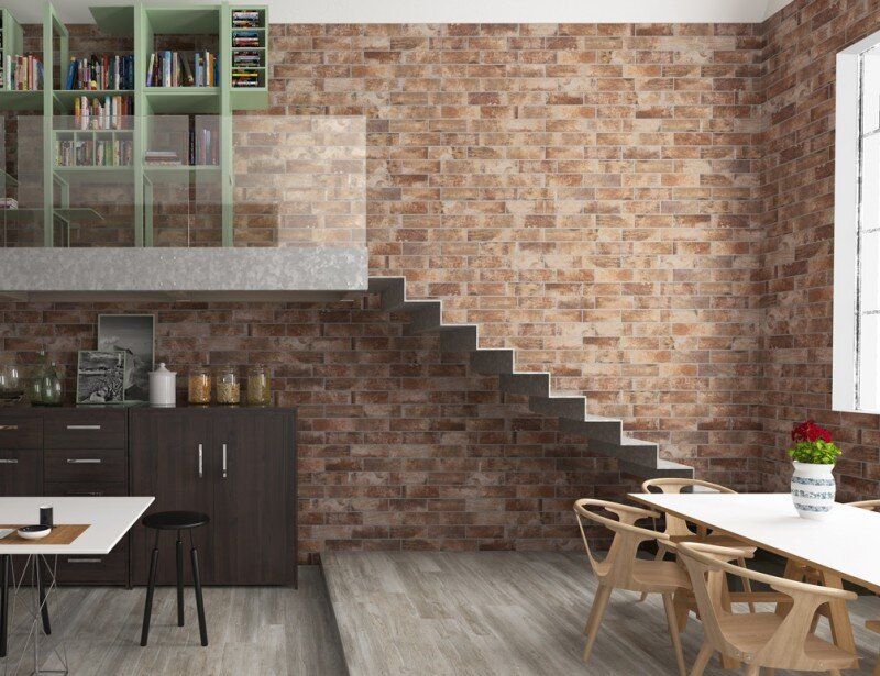 Brick wall interior with a floating staircase, bookshelf, dining area, and cabinetry.