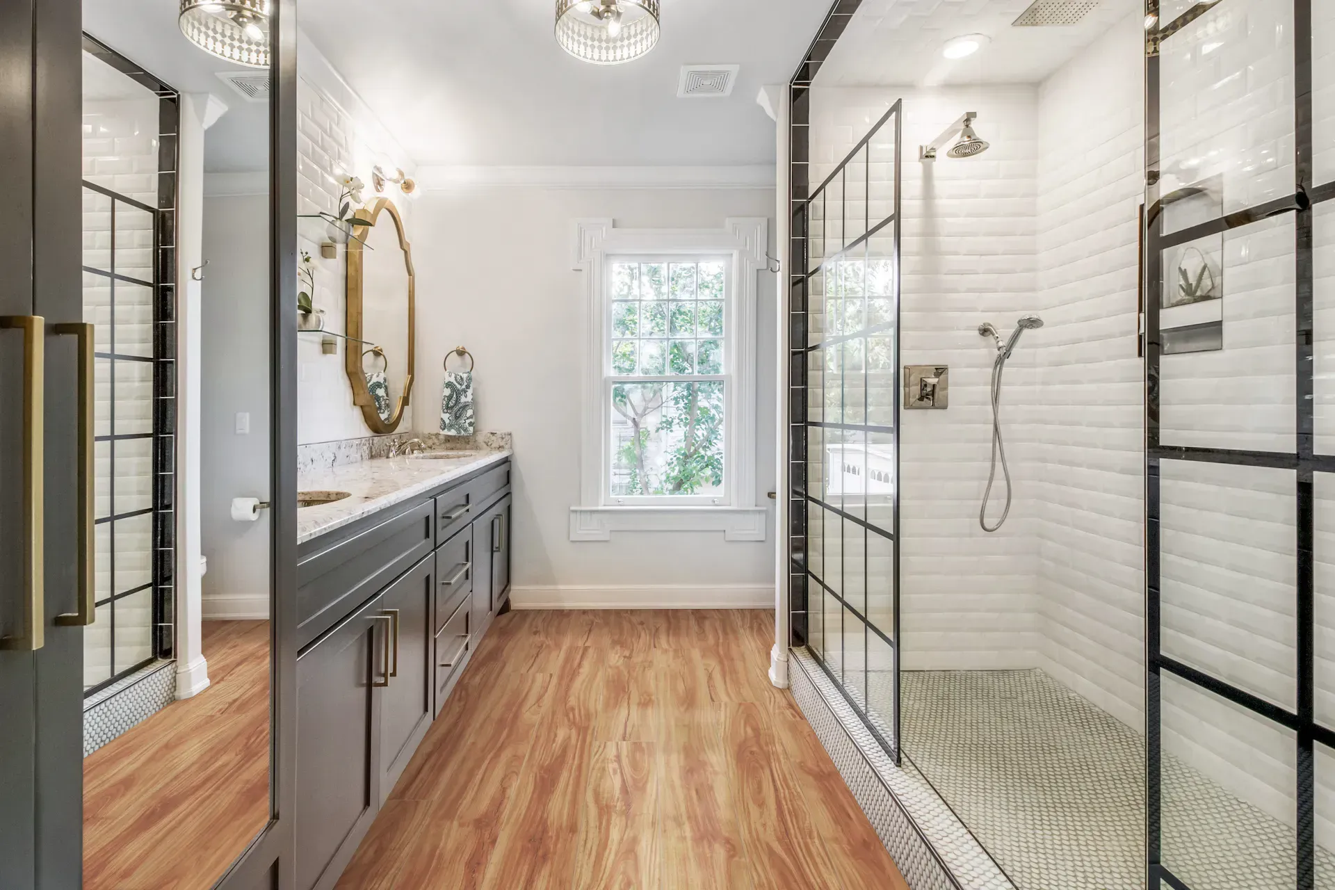 Bathroom with a long vanity, a large window, and a glass-walled shower.