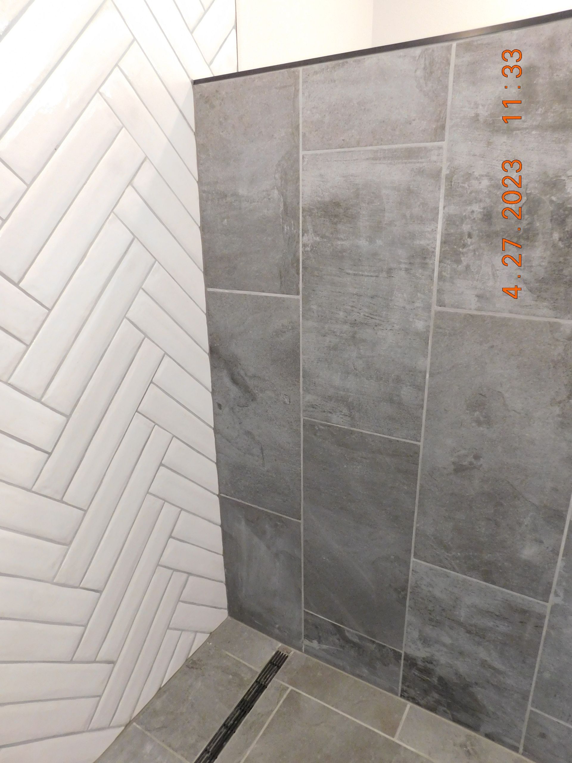Herringbone white tile meets vertical gray tile in a shower.